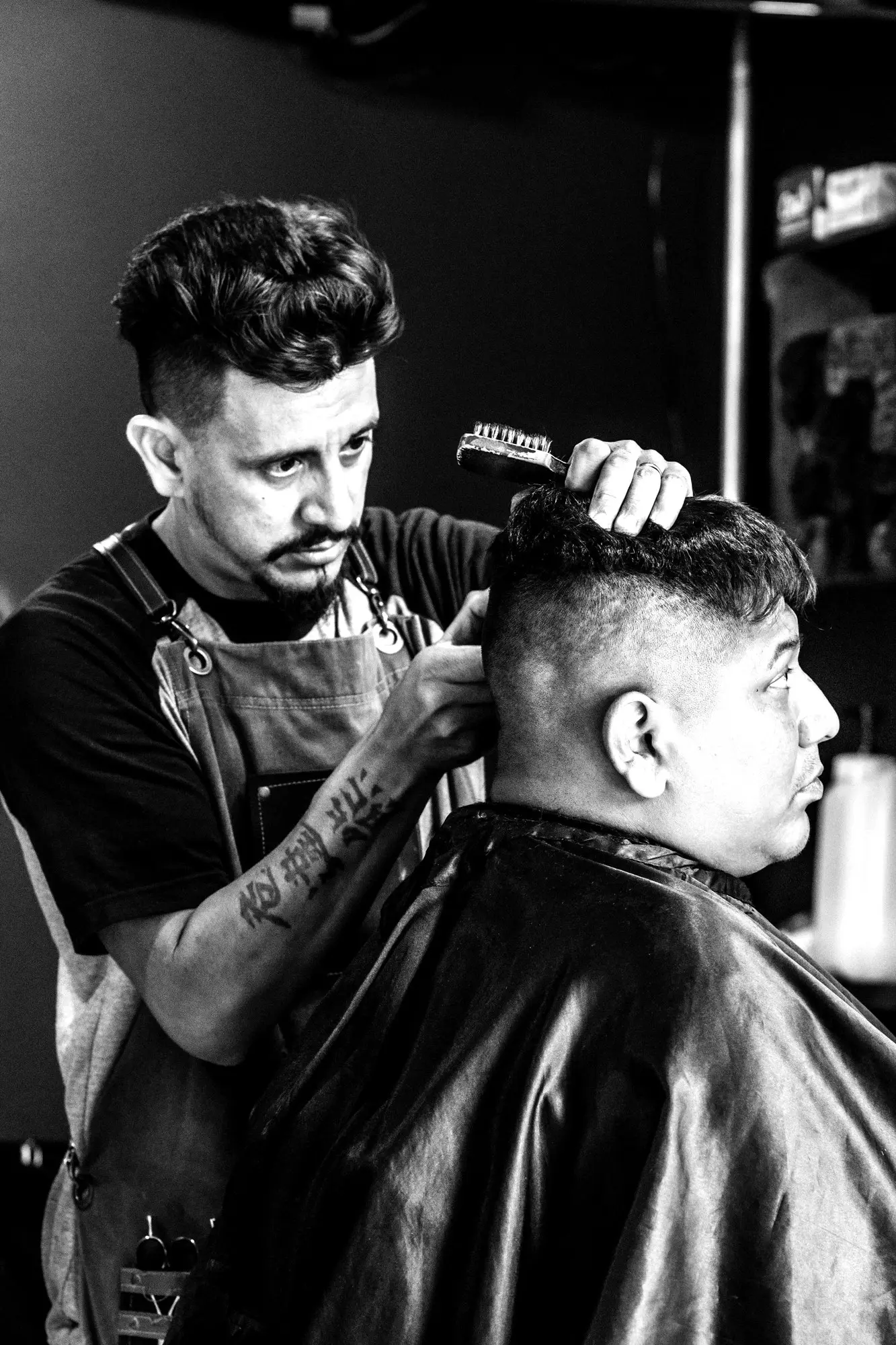 Barbero con mandil peinando a un cliente antes del corte